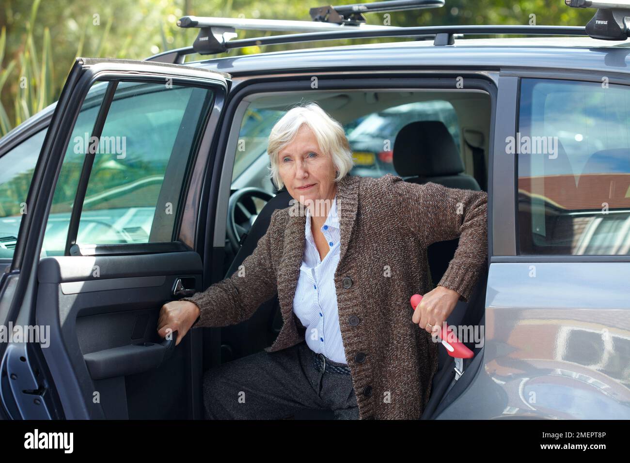 Femme sortant de la voiture, à l'aide d'une poignée portable montée dans le cadre d'une voiture Banque D'Images