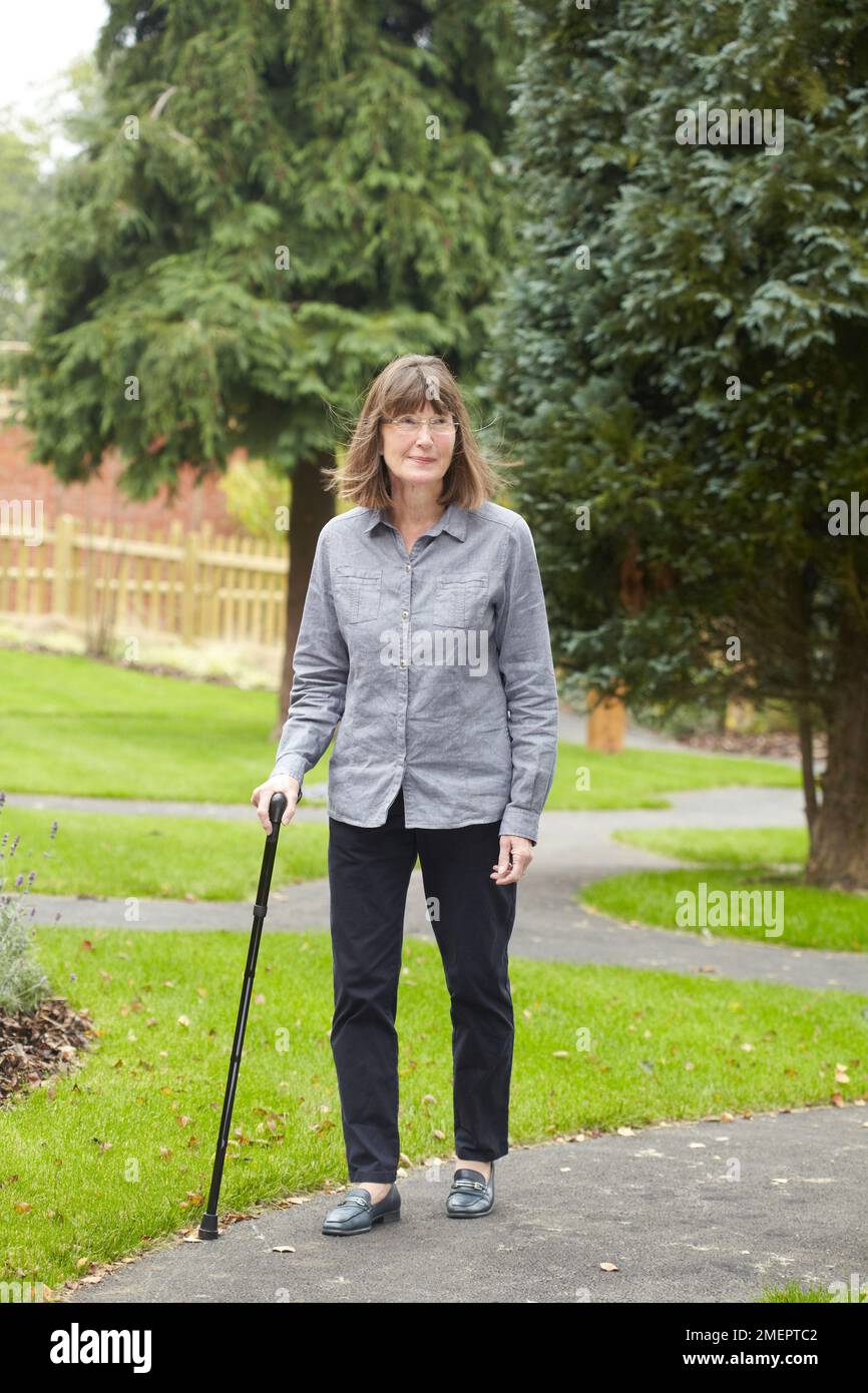 Femme utilisant un bâton de marche Banque D'Images