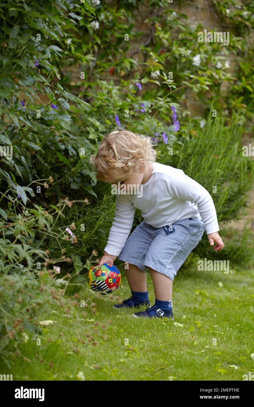 Garçon jouant avec le football dans le jardin, 2 ans 4 mois Banque D'Images