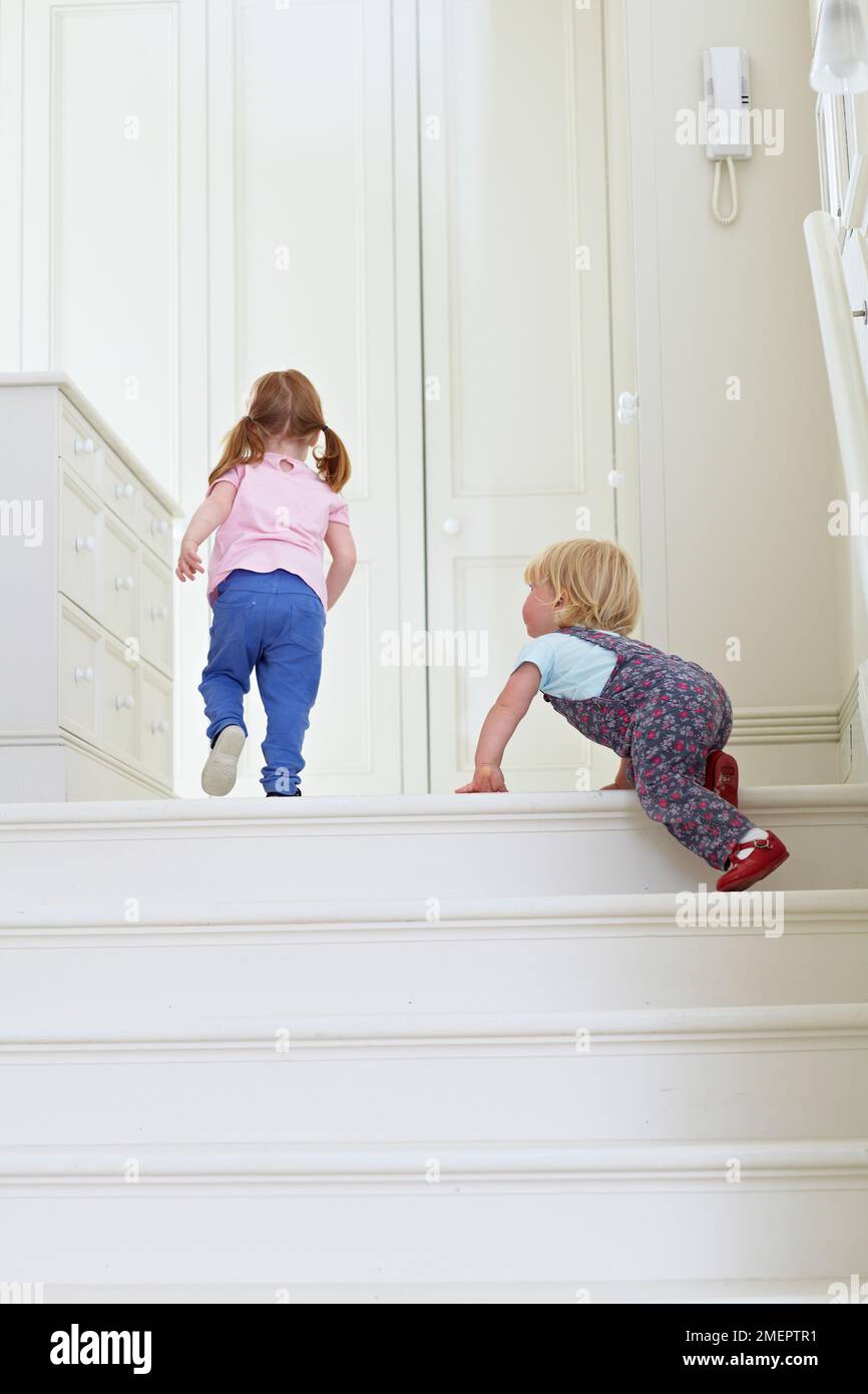 Jeune fille grimpant des escaliers avec un tout-petit, 2 ans et 18 mois Banque D'Images