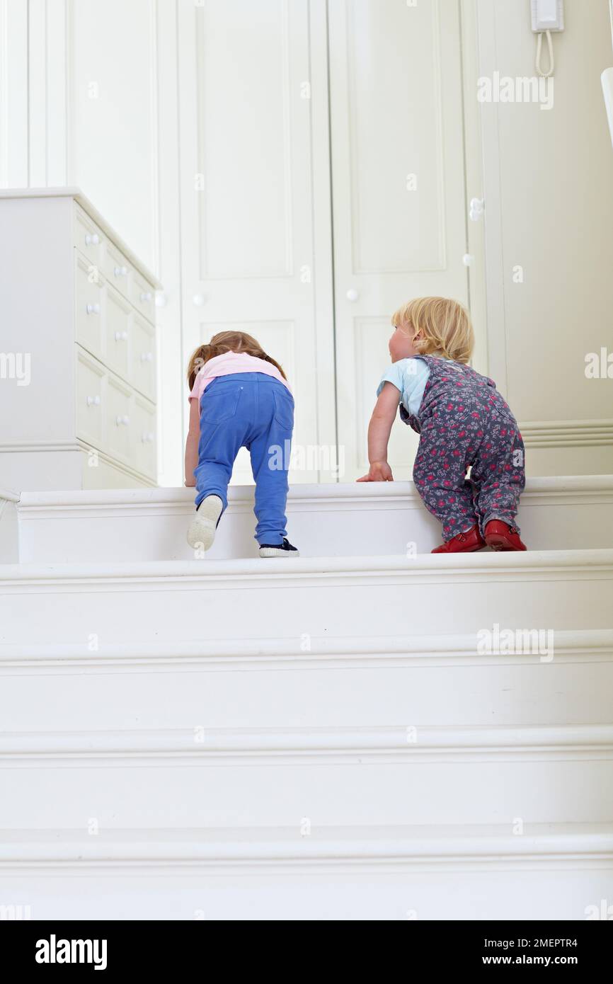 Garçon et fille grimpant les escaliers, 2 ans et 18 mois Banque D'Images