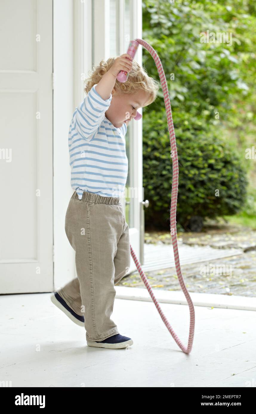 Garçon jouant avec corde à sauter, 2 ans 4 mois Banque D'Images