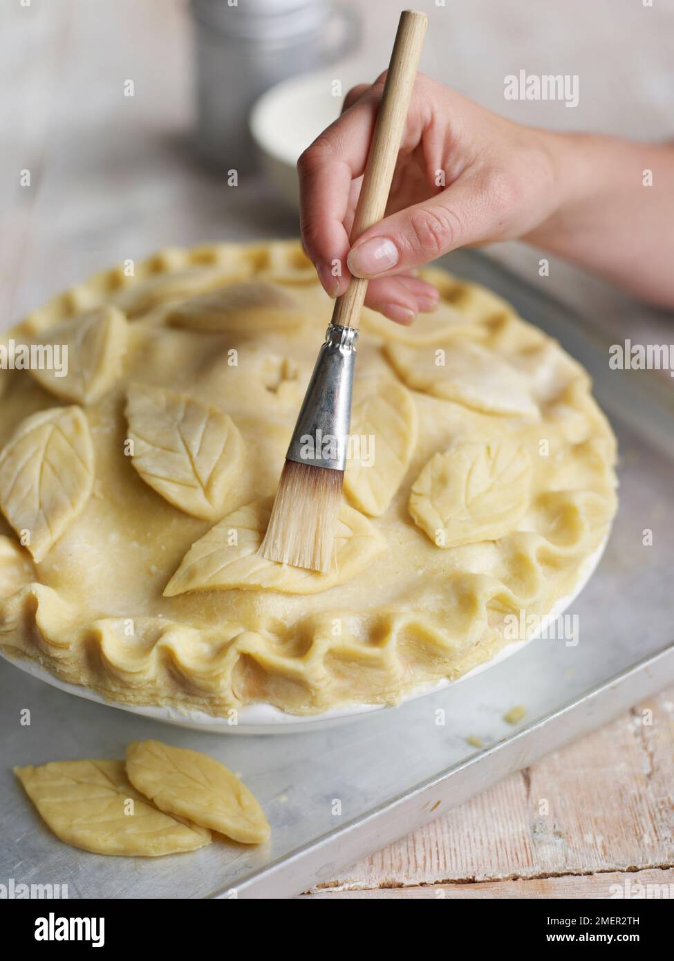 Le brossage à motifs de feuilles de pâte à tarte avec de l'eau Banque D'Images