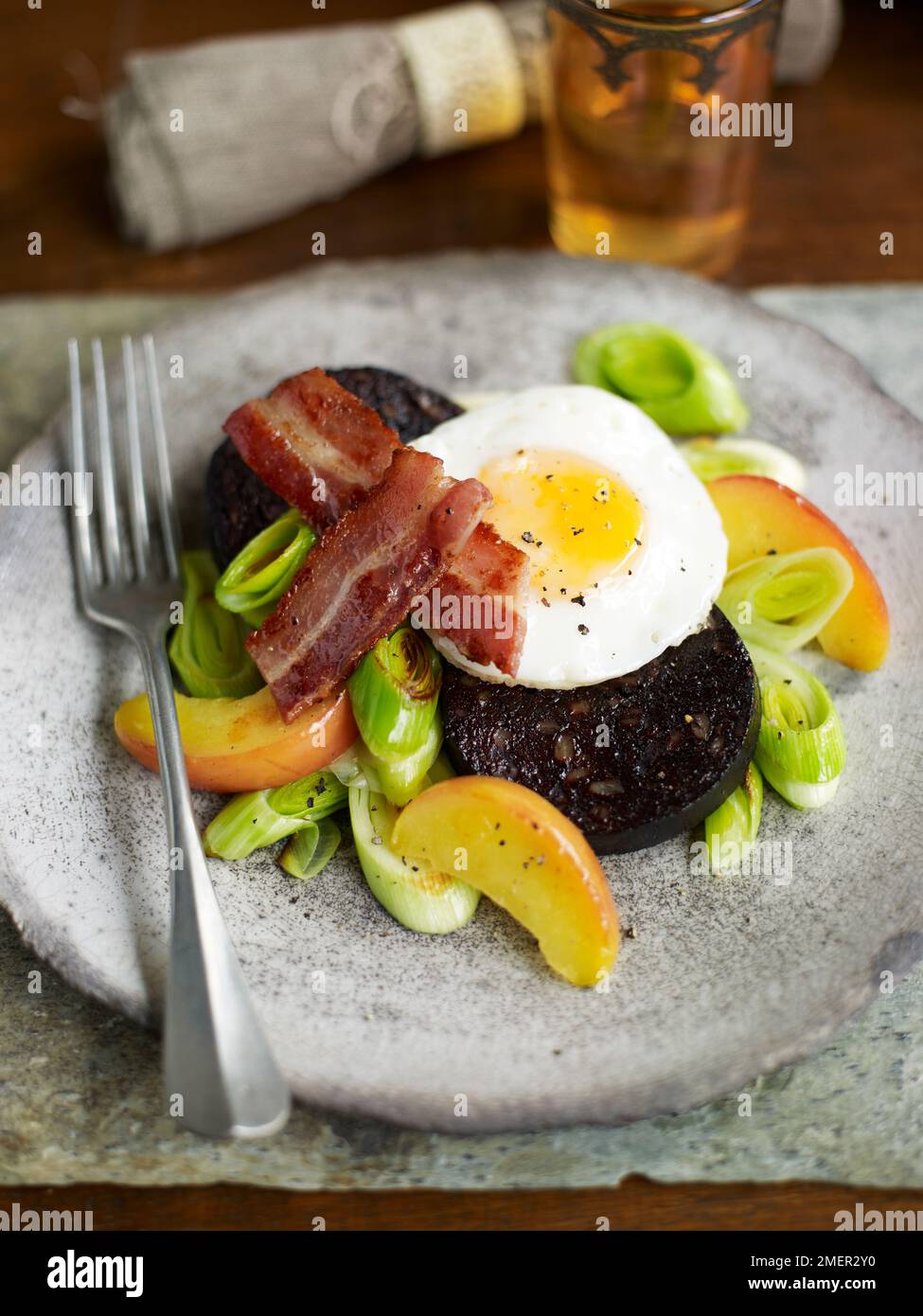 Pudding noir avec pommes, poireaux, œuf frit et bacon Banque D'Images