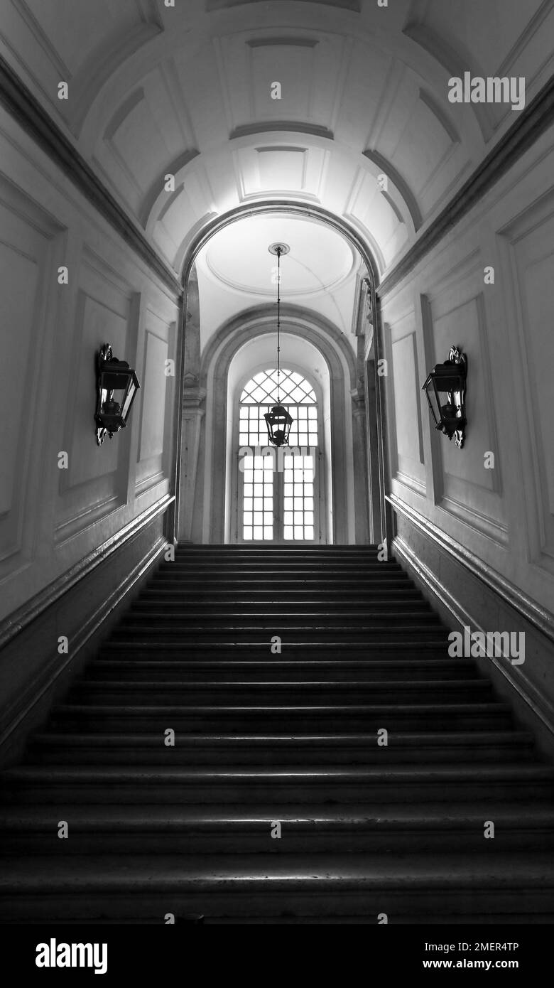 Mafra, Lisbonne, Portugal- 17 janvier 2023: Couloir, arches, Escalier en marbre et lampes du Palais - Couvent de Mafra. Image monochrome Banque D'Images