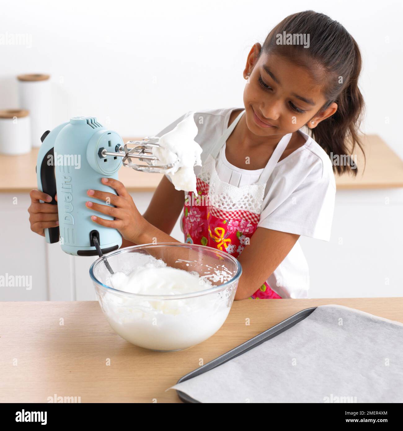 Fille fouetter des blancs d'œufs avec un fouet électrique, 8 ans Banque D'Images