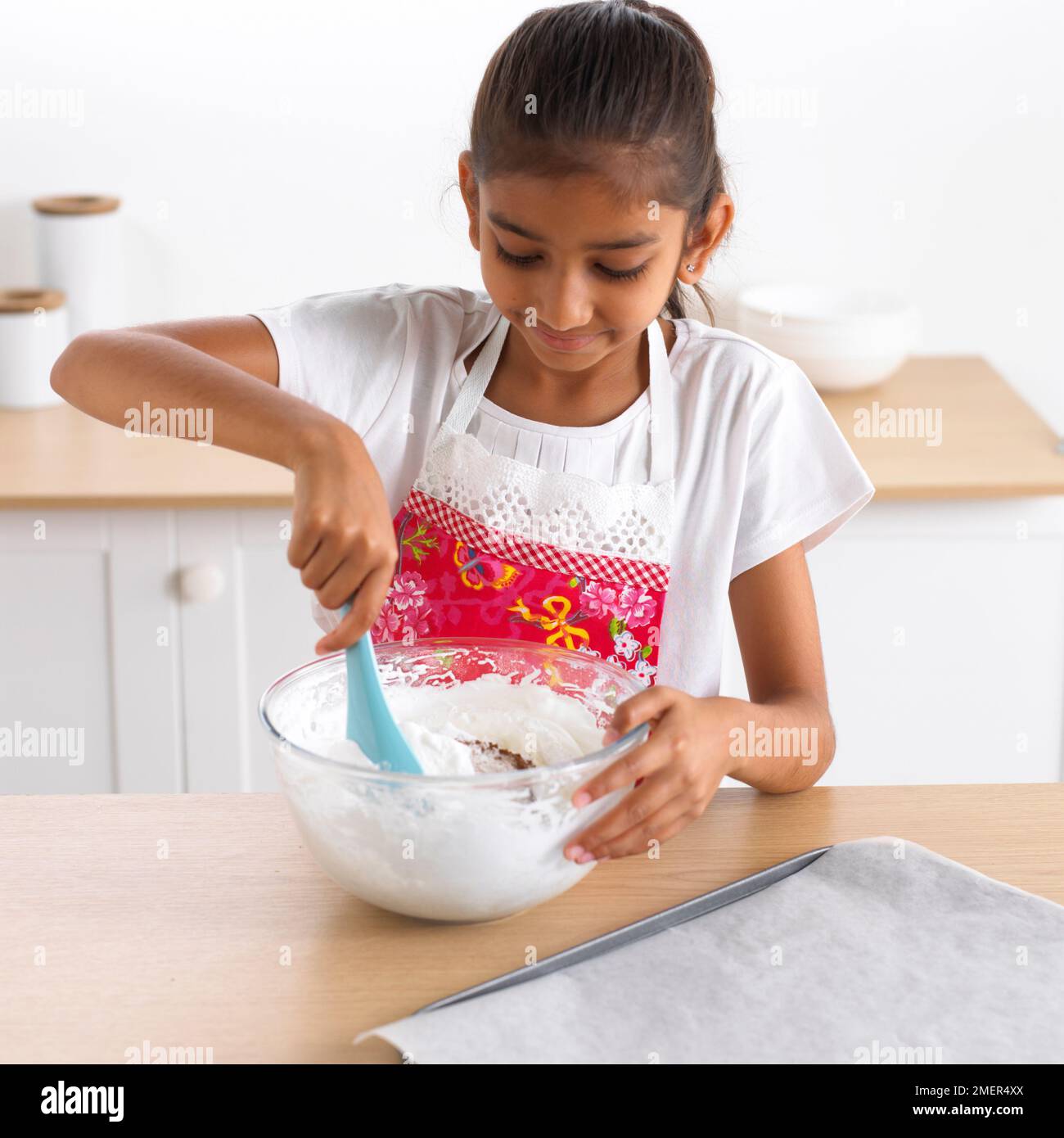 Fille remuant blancs d'oeufs fouettés, 8 ans Banque D'Images