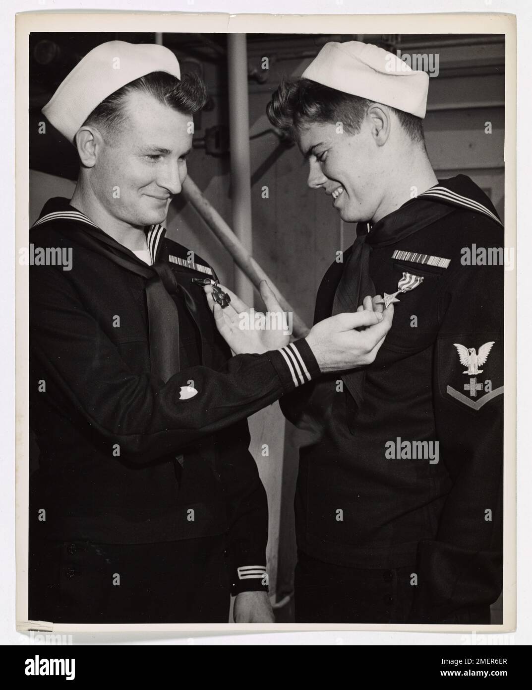 Le garde-côtes américain P.L. Clark et le marin C.C. Curry admirent mutuellement les médailles reçues pour héroïsme lors de la campagne nord-africaine. Clark a reçu la Navy Cross pour son courage sous le feu ennemi, tandis que Curry a reçu l'étoile d'argent pour sa bravoure dans le traitement des blessés. Banque D'Images