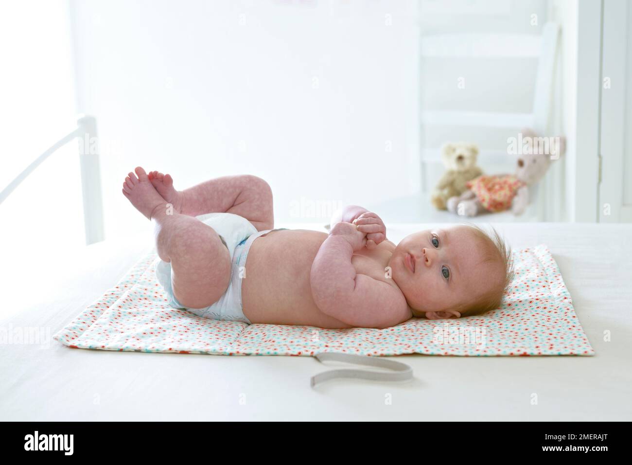 Bébé fille allongé sur un tapis à langer, 3 mois Banque D'Images