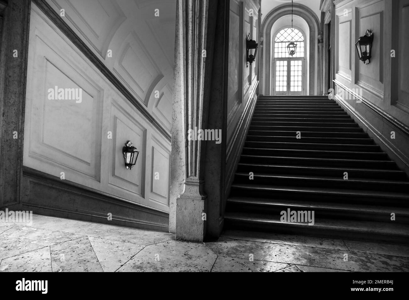 Mafra, Lisbonne, Portugal- 17 janvier 2023: Couloir, arches, Escalier en marbre et lampes du Palais - Couvent de Mafra. Image monochrome Banque D'Images