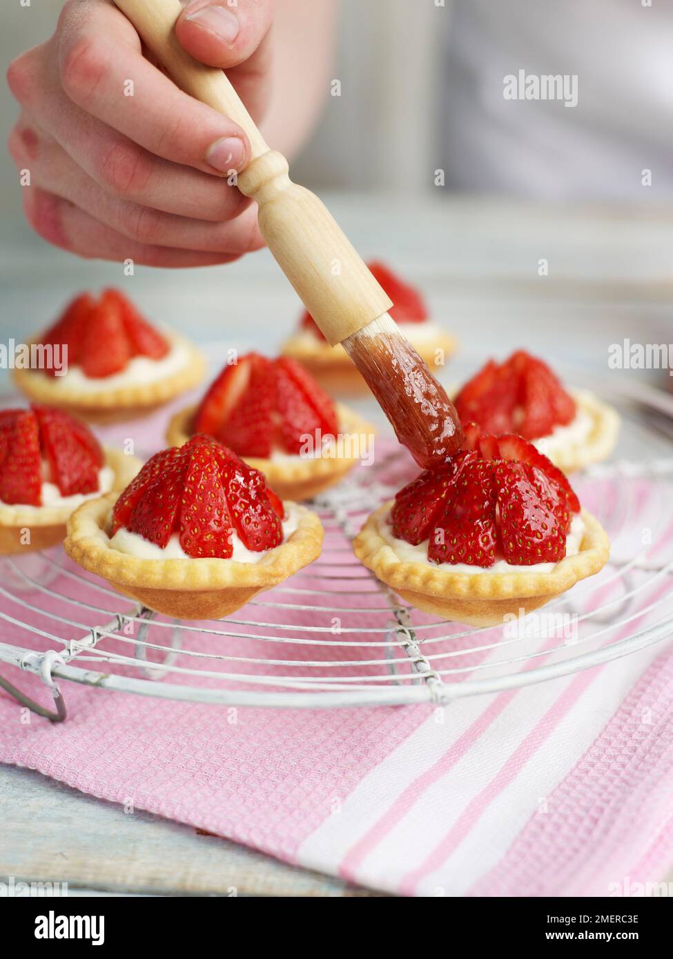 Glaçage des tartes à la fraise, à l'aide d'un pinceau à pâtisserie Banque D'Images