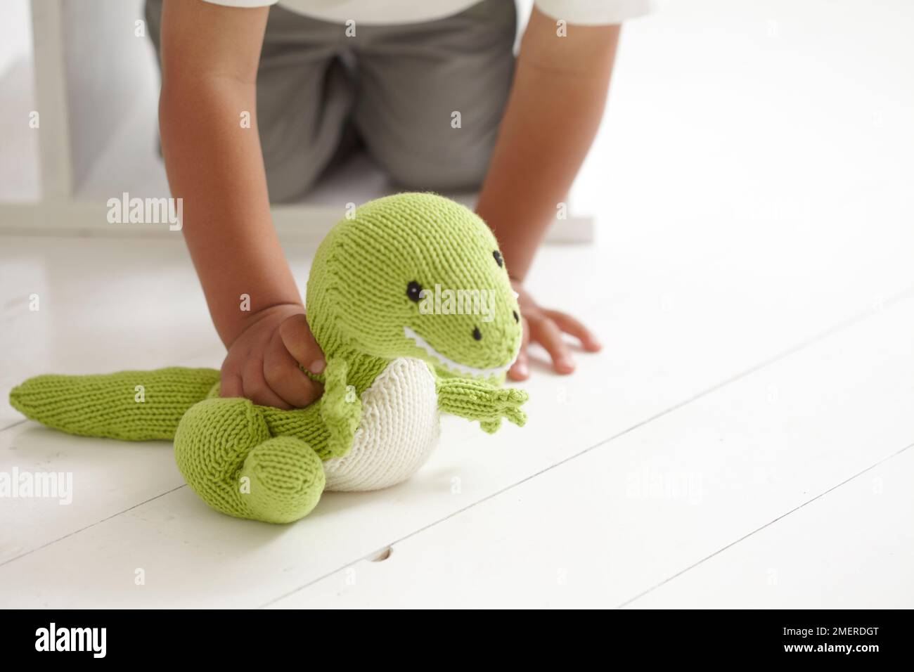Garçon jouant avec un jouet de dinosaure tricoté, 3 ans Banque D'Images