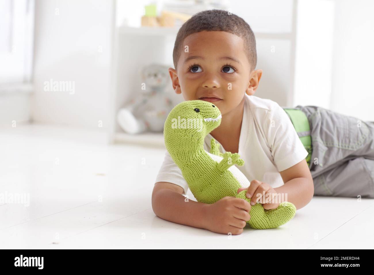 Garçon jouant avec un jouet de dinosaure tricoté, 3 ans Banque D'Images