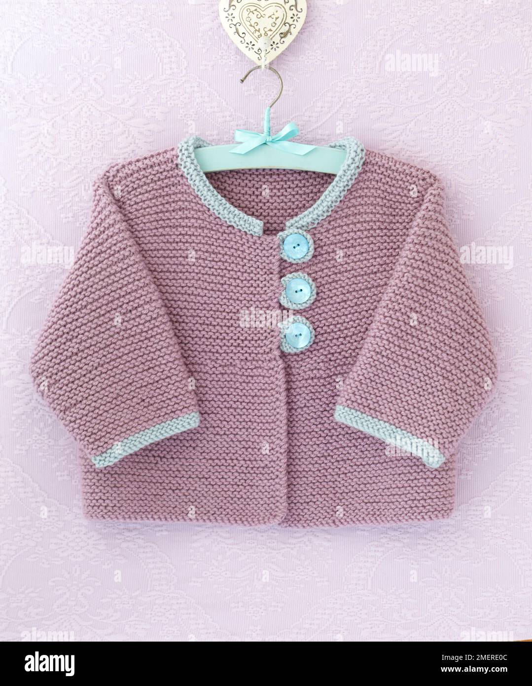 Veste en maille à motif de matinee accrochée à un cintre Banque D'Images