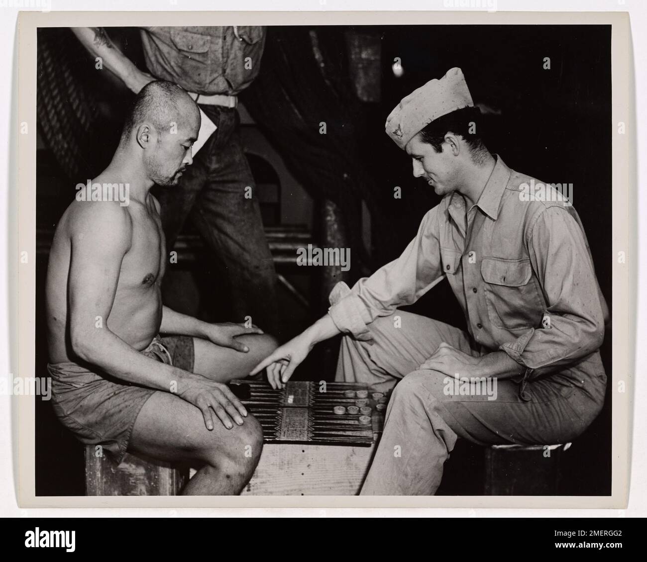 Un soldat coréen à bord d'un transport d'invasion habité par les garde-côtes apprend à jouer le jeu américain d'Acey-Deucy. L'image reflète l'échange culturel et la camaraderie entre les soldats de différents horizons pendant le service militaire. Banque D'Images