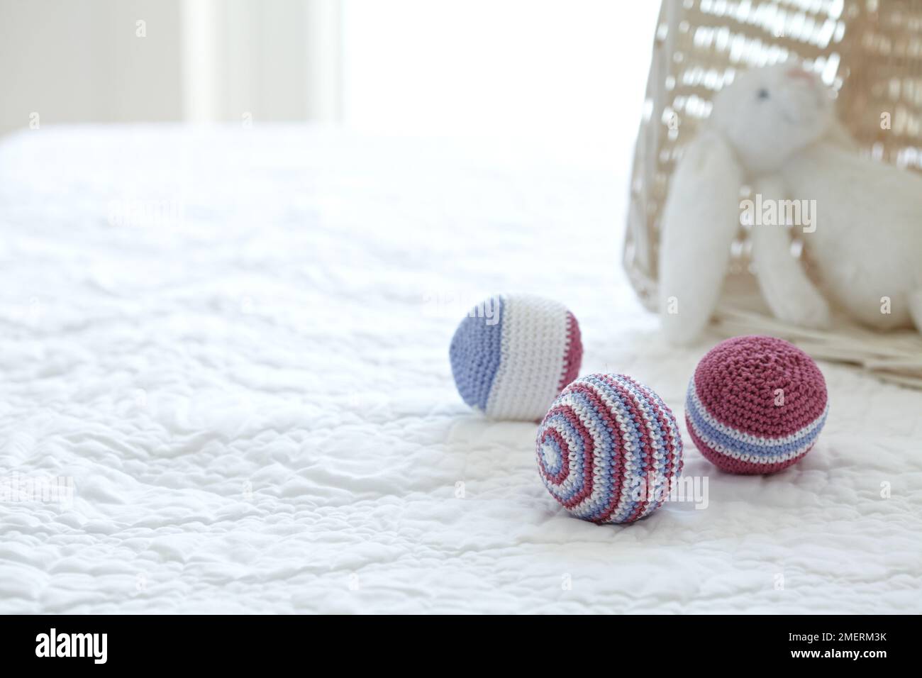 Boules de jouet en bonneterie et lapin en peluche sur un lit Banque D'Images