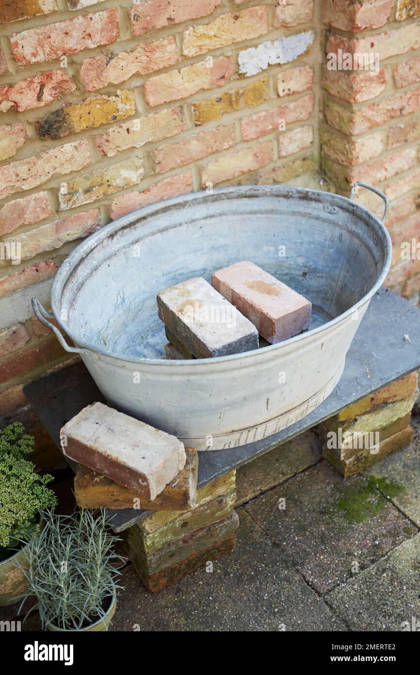 Placer des briques au centre d'un bain en acier galvanisé d'époque Banque D'Images
