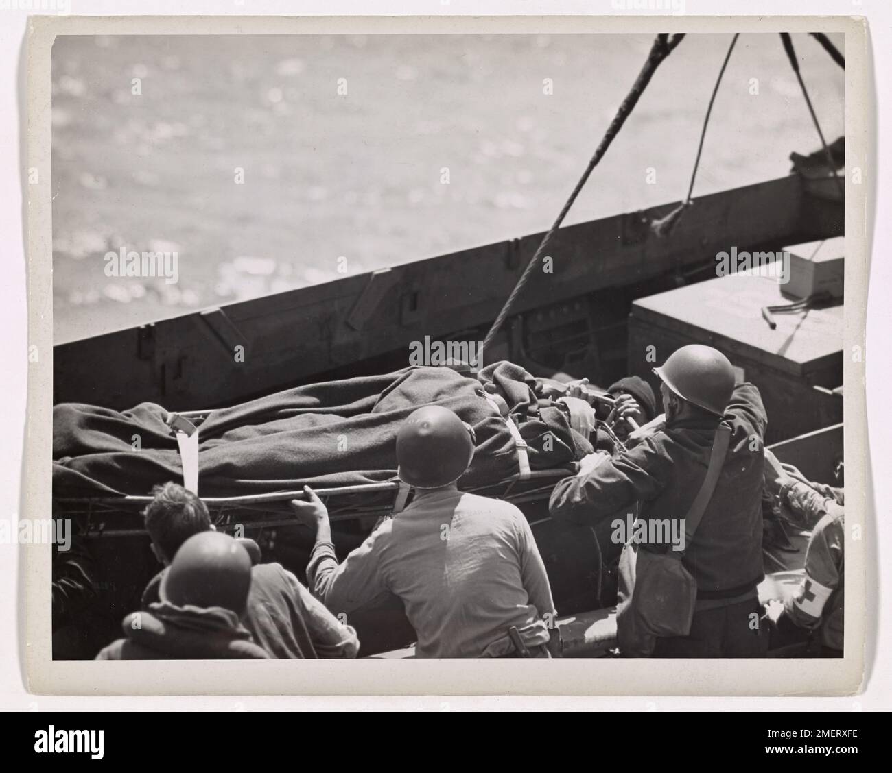 Aide des gardes-côtes victimes de la première invasion. Les membres d'équipage d'un transport d'assaut de la Garde côtière transfèrent les alliés blessés d'un engin d'atterrissage à leur navire au large de la côte française. Banque D'Images