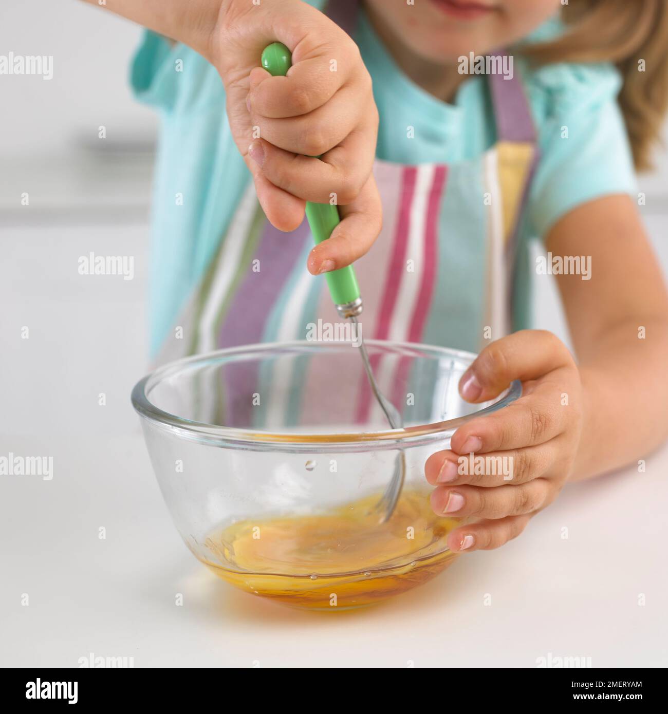 Fille battant et oeuf avec le sirop dans un bol Banque D'Images