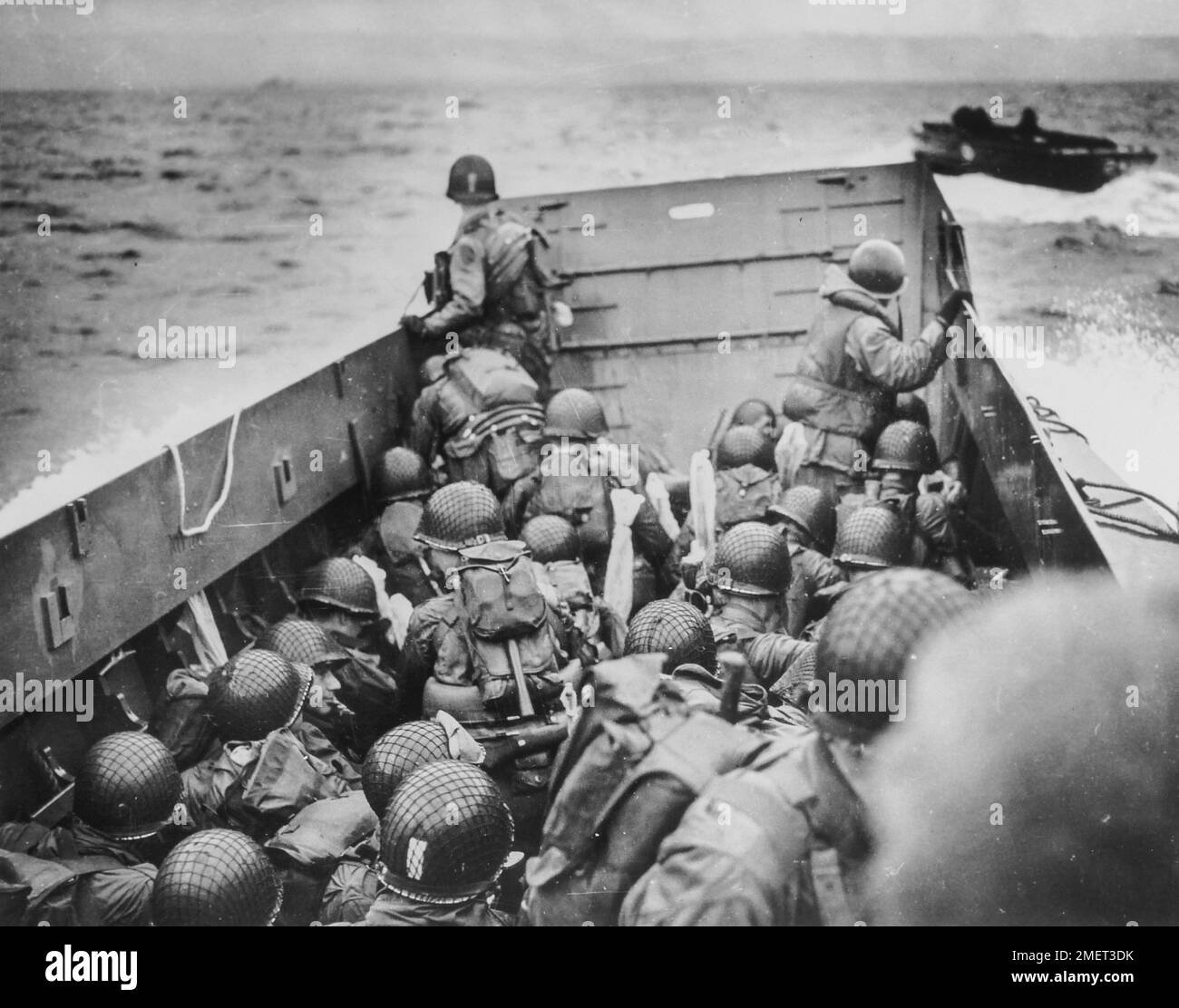 Photographie des soldats qui s'accroupient derrière les remparts d'une barge de débarquement de la Garde côtière. French Coast Dead Ahead - crouch des soldats Yankees, serré, derrière les remparts d'une barge d'atterrissage de la Garde côtière dans le balayage historique à travers la Manche jusqu'aux rives de la Normandie. Quelques minutes plus tard, ils ont balayé la plage sous le feu des défenseurs nazis. Ces barges de la Garde côtière ont roulé d'avant en arrière à travers le jour J amenant une vague de renforts à la tête de plage. 1939 - 1967. Banque D'Images