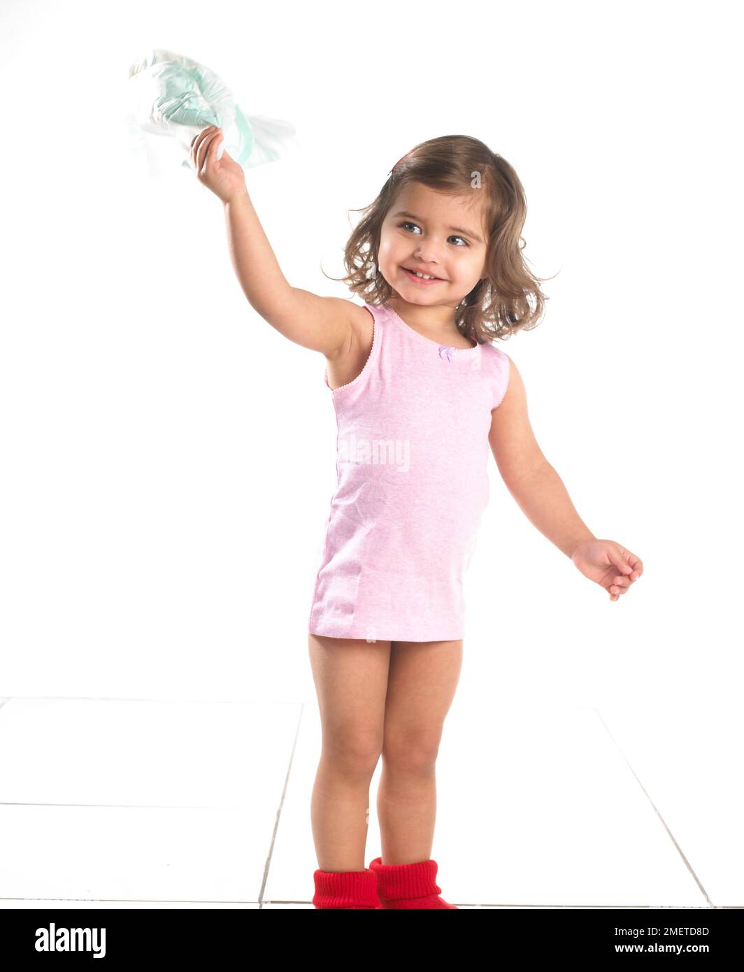 Fille portant un gilet rose et des pantoufles rouges debout tenant une couches, 20 mois Banque D'Images Fille portant un gilet rose et des pantoufles rouges debout tenant une couches, 20 mois Banque D'Images