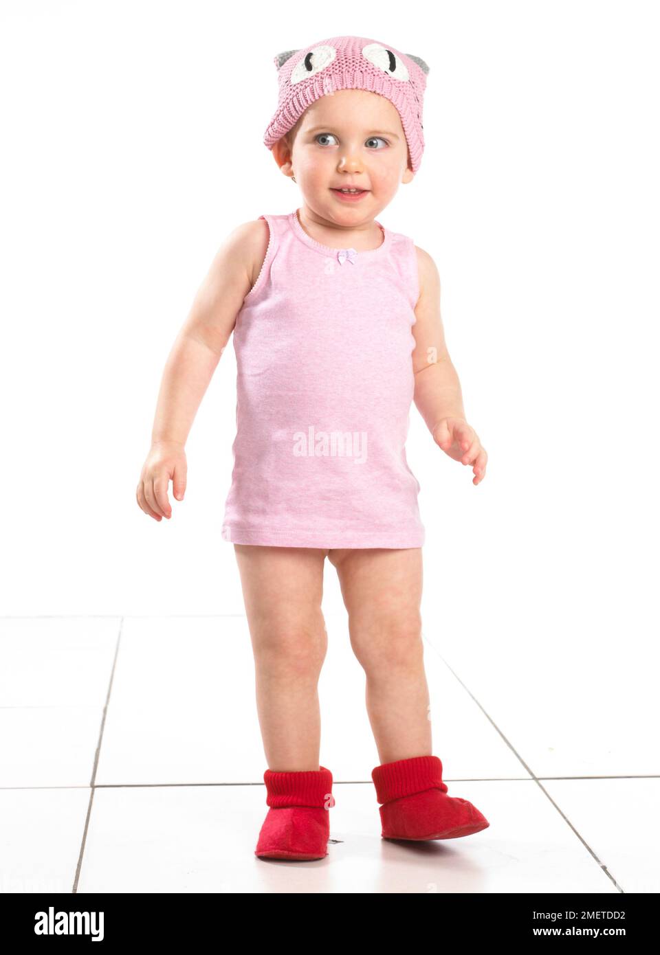 Fille portant des chaussettes rouges, haut rose et chapeau de laine rose, 19 mois Banque D'Images