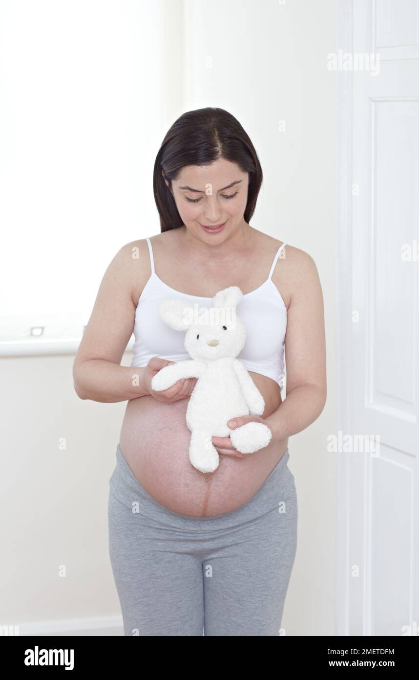 Femme enceinte tenant un jouet doux Banque D'Images