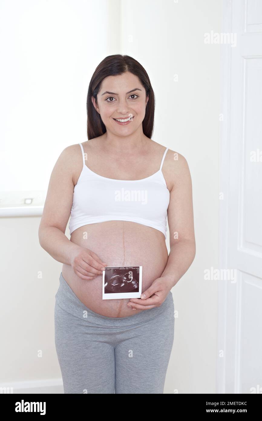 Femme enceinte tenant une échographie au-dessus de son ventre Banque D'Images