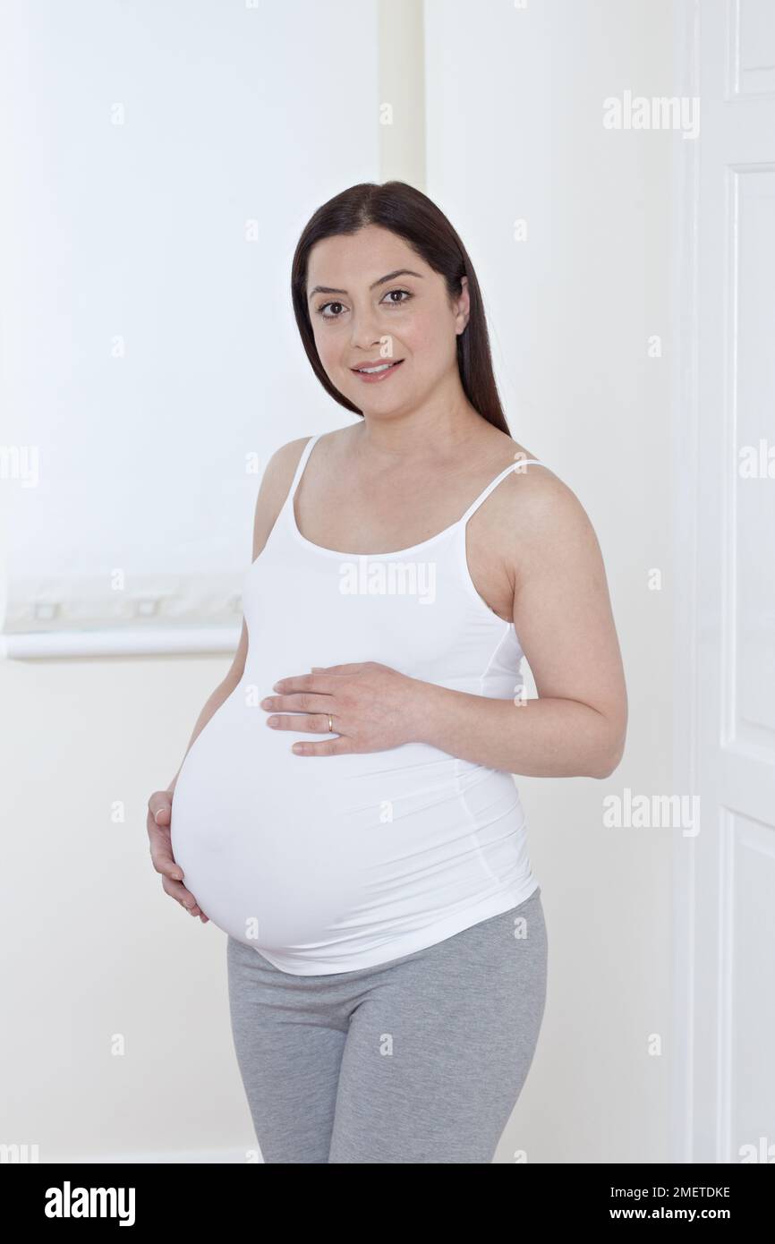 Femme enceinte, regardant l'appareil photo Banque D'Images