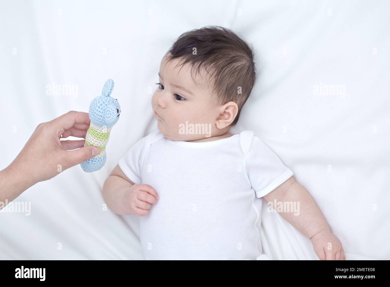 Bébé fille (16 semaines) être montré tricoté jouet doux Banque D'Images