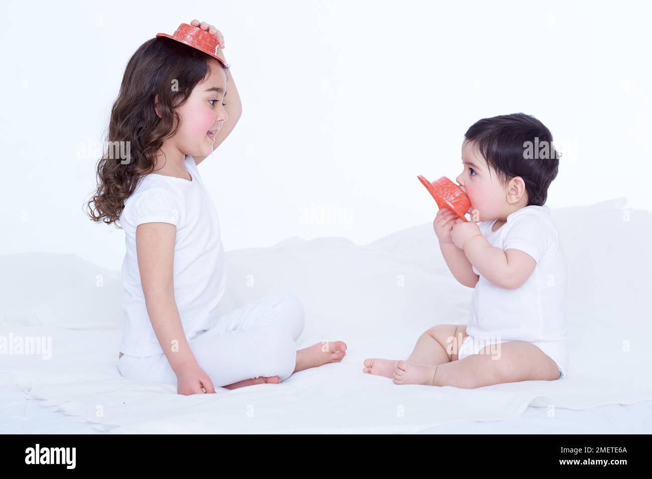 Petite fille (40 semaines) et sa sœur (3,5 ans) jouant avec des chapeaux en plastique Banque D'Images