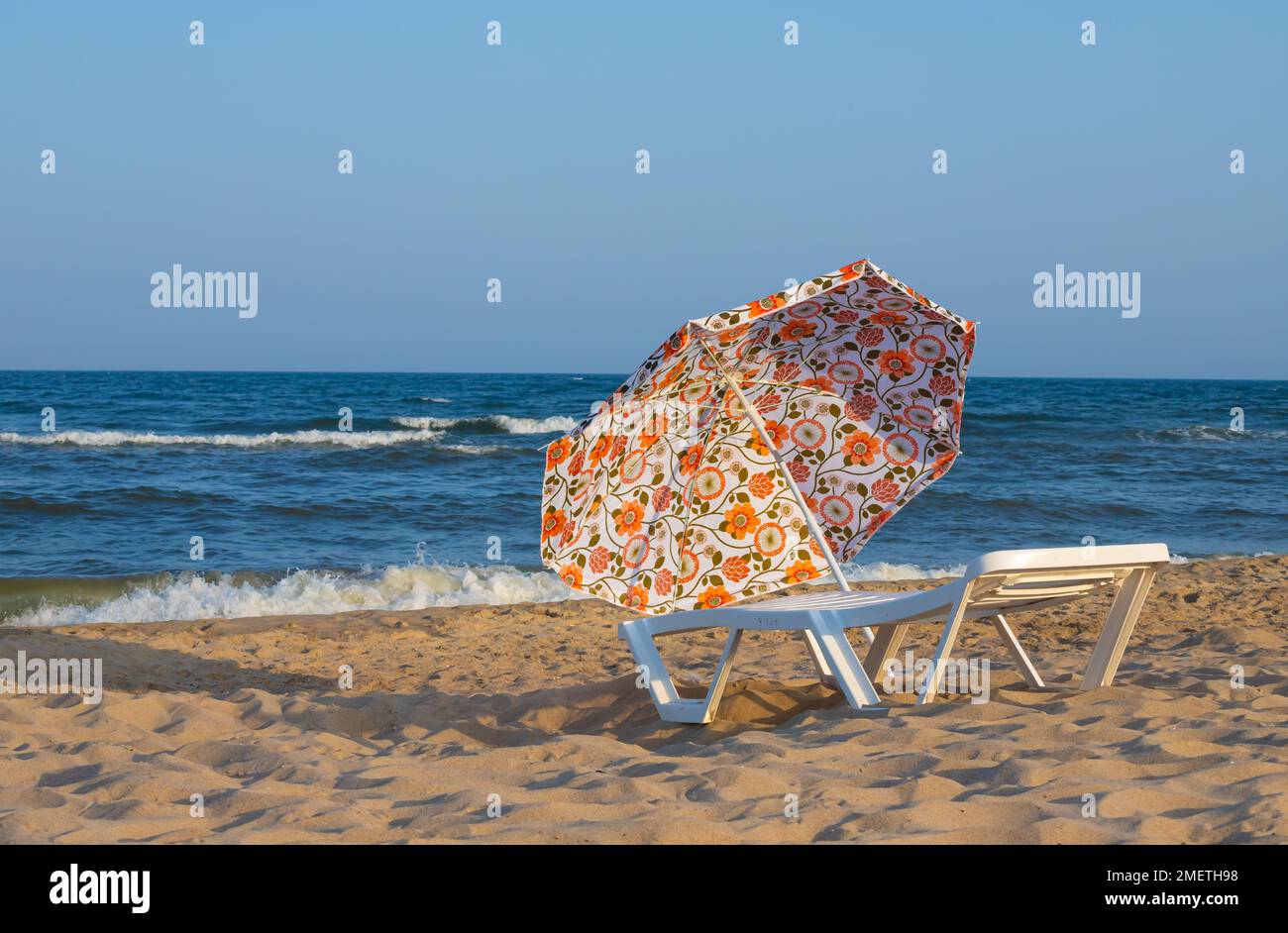 Parasol du soleil et chaises longues sont sur la plage contre la mer bleue, les chaises longues sont des serviettes. Banque D'Images