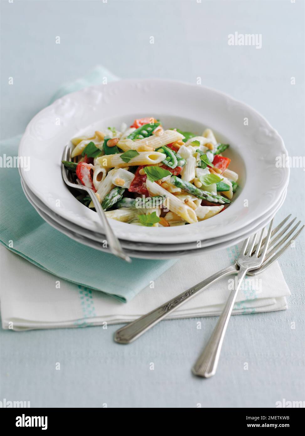 Pâtes primavera, penne aux pointes d'asperges, pois sugarsnap, poivrons rouges, pignons de pin en sauce crémeuse, garni de feuilles de basilic Banque D'Images