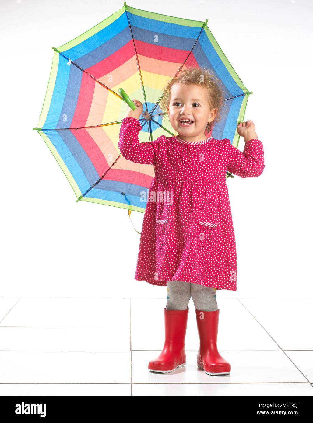 Petite fille (2 ans) portant des bottes wellington et holding umbrella Banque D'Images