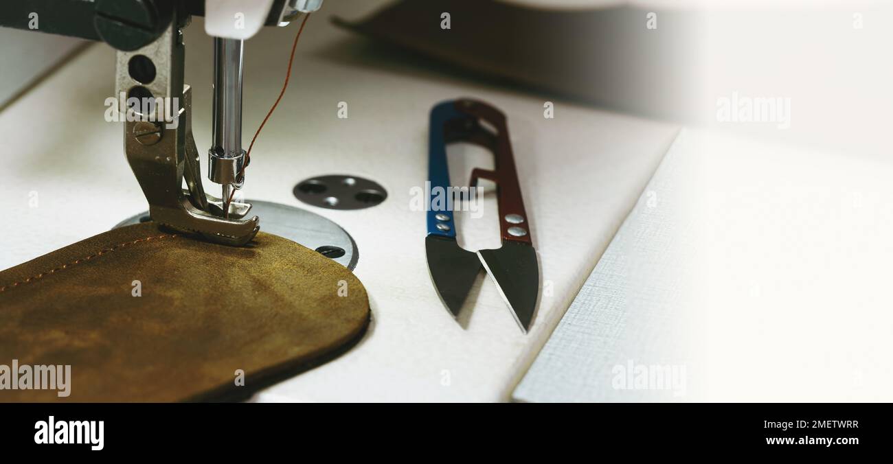 Couture d'un article en cuir écologique. Gros plan de la machine à coudre et morceau de cuir écologique. Machine à coudre, personnalisation, concept de petite entreprise. Atelier d'artisans Banque D'Images