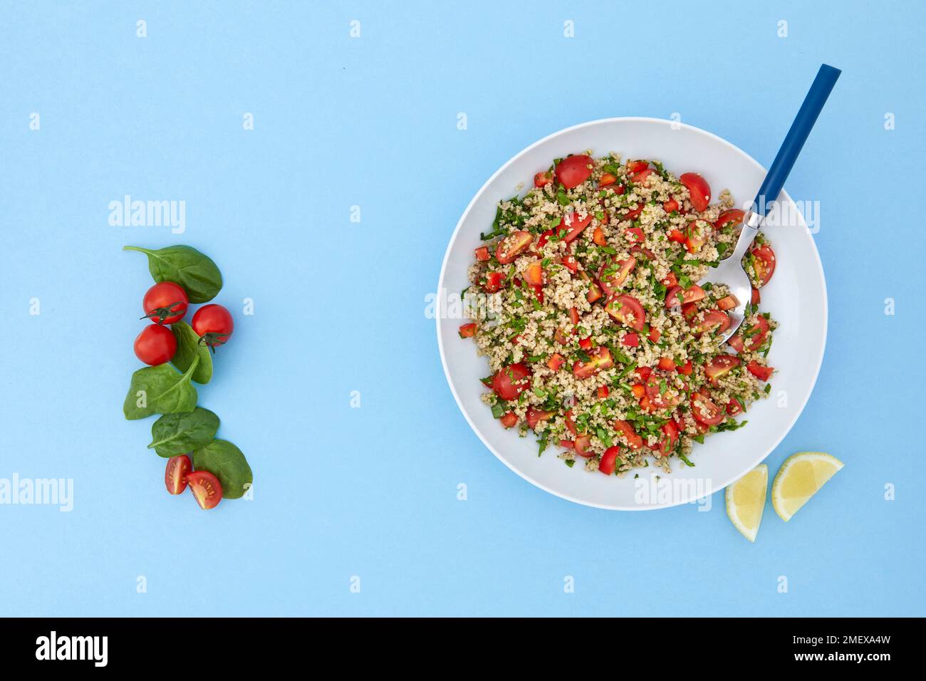 Salade couscous aux épinards et aux tomates sur fond bleu Banque D'Images