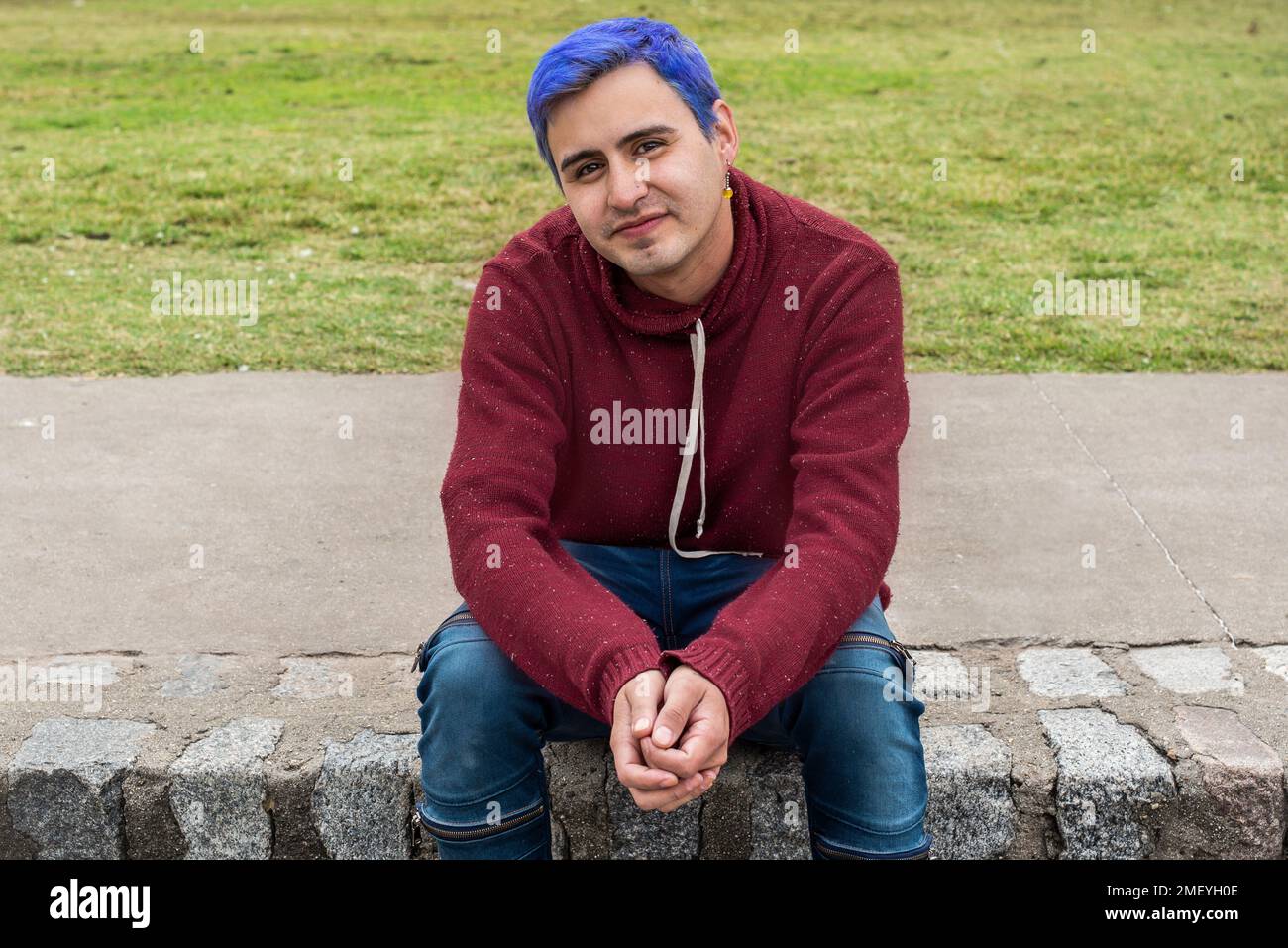 Portrait d'un jeune homme aux cheveux bleus regardant l'appareil photo à l'extérieur Banque D'Images