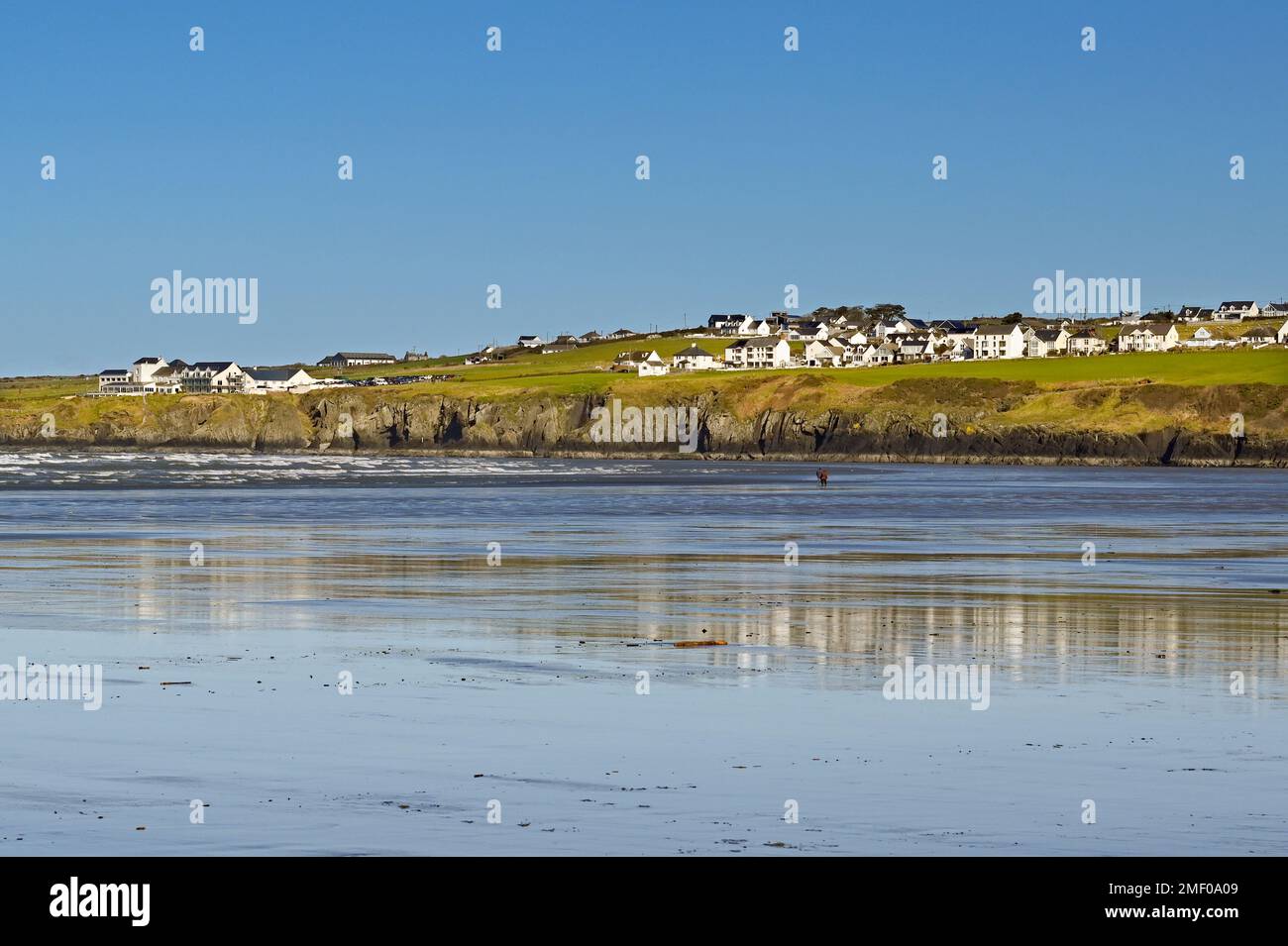 Poppit Sands, Cardigan, pays de Galles - Mars 2022: Sable humide sur la plage à marée basse, avec Gwbert sur la mer en arrière-plan. L'hôtel Cliff se trouve sur la gauche. Banque D'Images