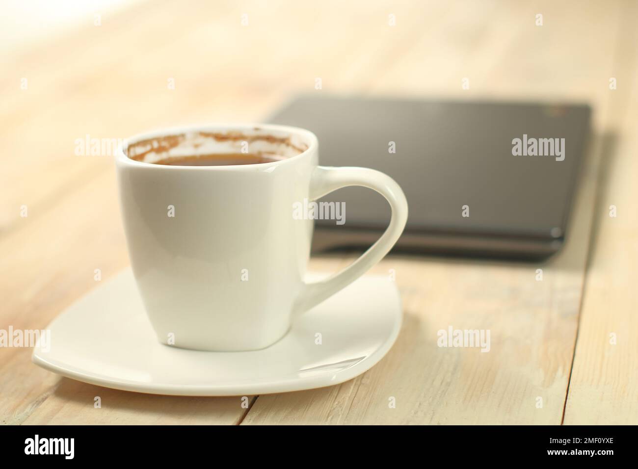 une tasse de café sur l'arrière-plan d'un ordinateur portable et une table en planches Banque D'Images