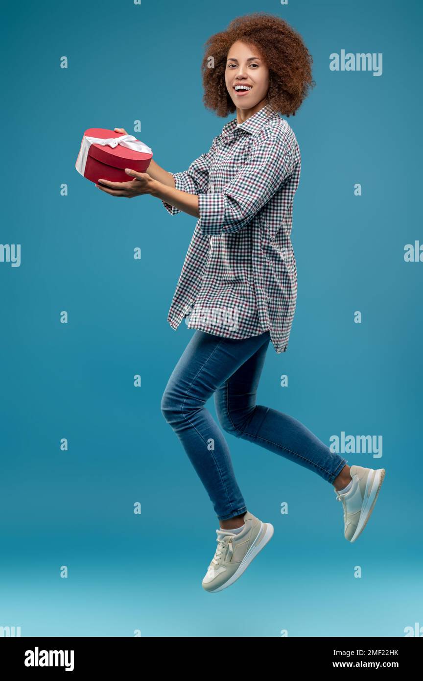 Jeune femme mignonne avec une boîte cadeau dans les mains ayant l'air excitée Banque D'Images