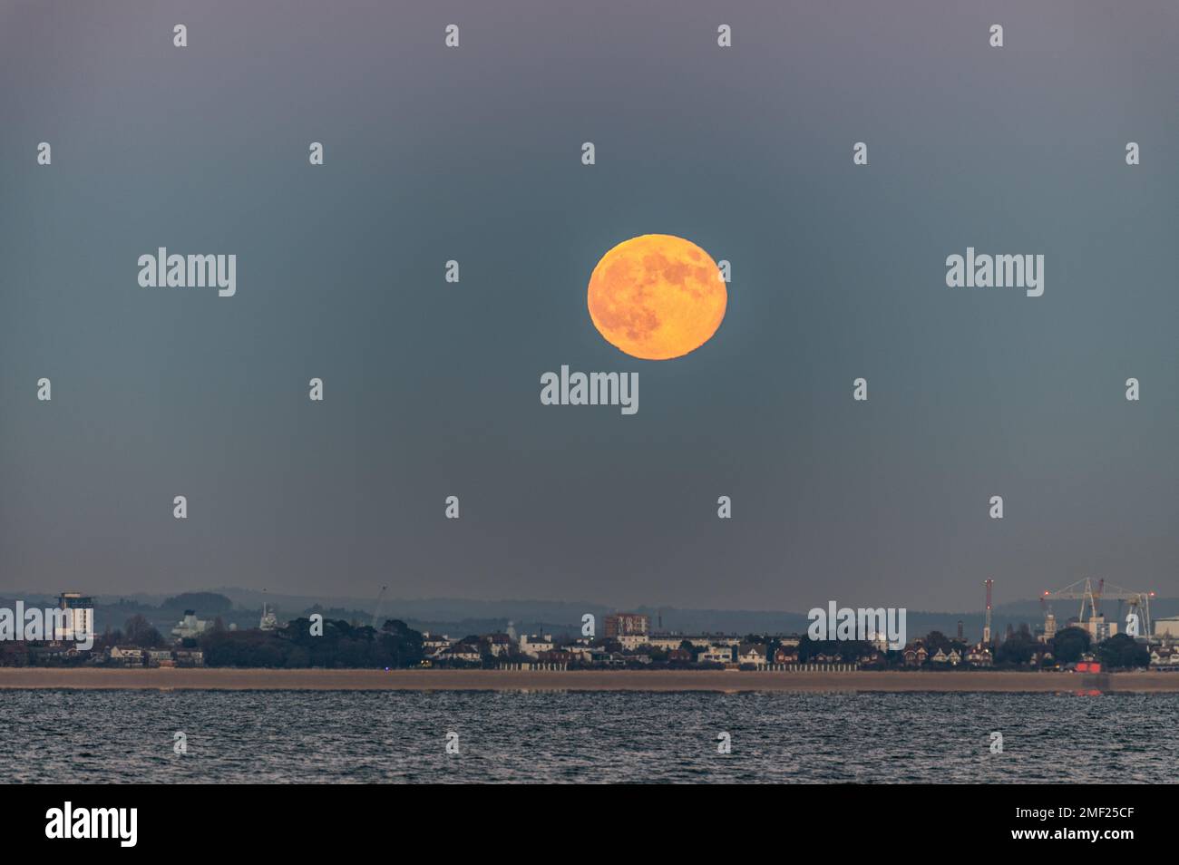 Pleine lune s'élevant au-dessus de Gosport et Portsmouth depuis Woodside Bay, Wootton, Isle of Wight. Banque D'Images