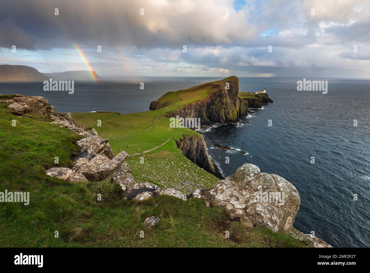 Vue panoramique spectaculaire sur le phare de Neist point lorsque les averses de pluie tombent des nuages moody. Île de Skye, Écosse, Royaume-Uni. Banque D'Images