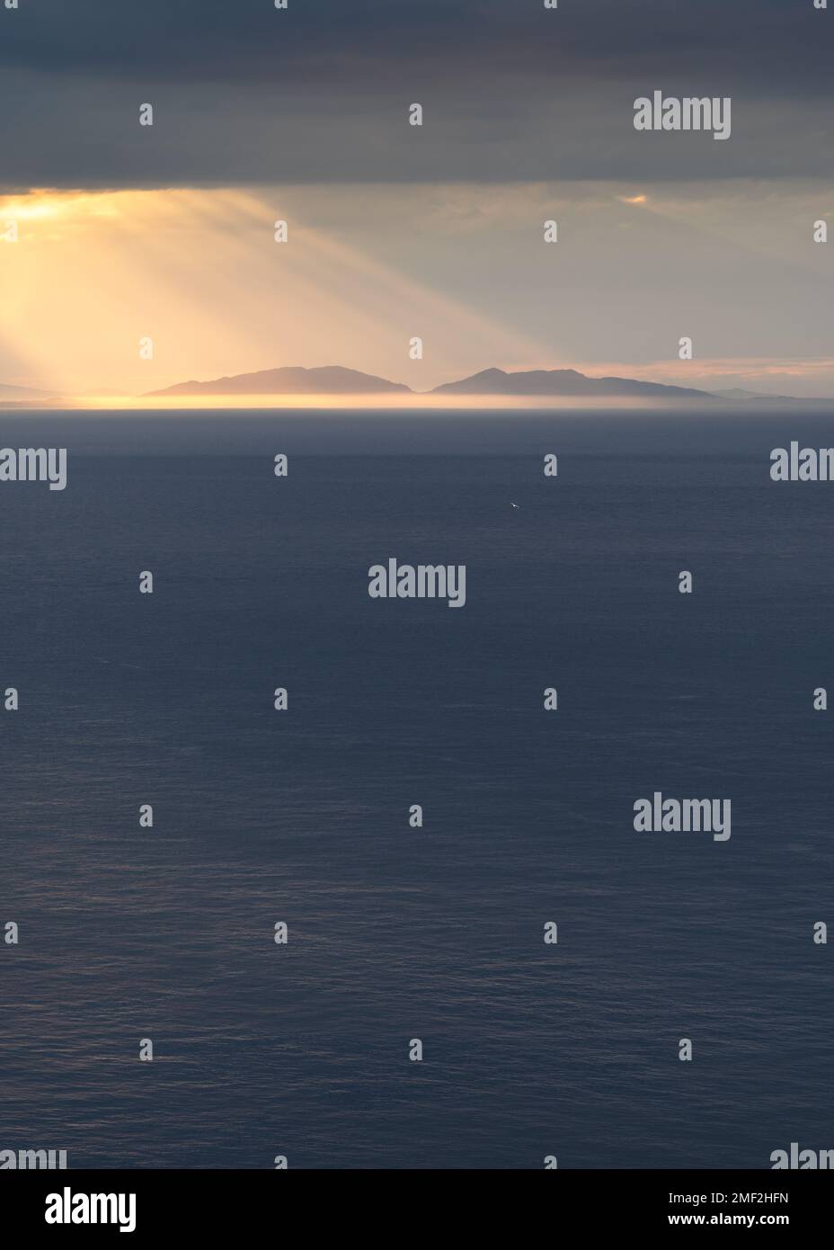 De beaux rayons de soleil qui brillent à travers des nuages sombres sur les Hébrides extérieures écossaises au loin. Île de Harris, Écosse, Royaume-Uni. Banque D'Images