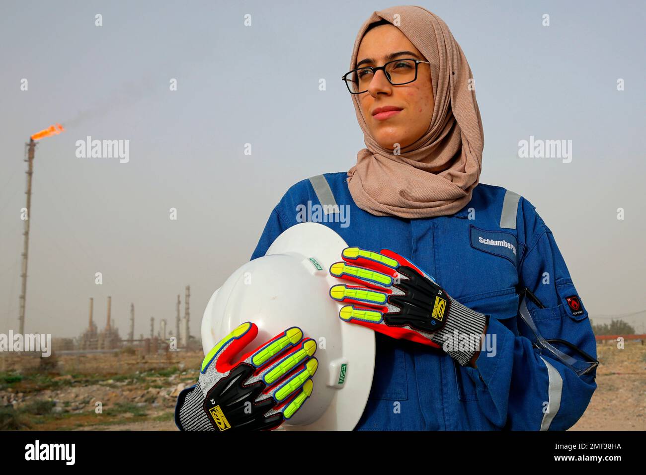 Zainab Amjad, a petrochemical engineer, poses for a photo near an oil field outside Basra, Iraq, Monday, Feb. 18, 2021. Amjad is among just a handful of women who have eschewed the dreary office jobs typically handed to female petrochemical engineers in Iraq. Instead, they chose to become trailblazers in the country's oil industry, taking up the grueling work of drilling. (AP Photo/Nabil al-Jourani) Banque D'Images