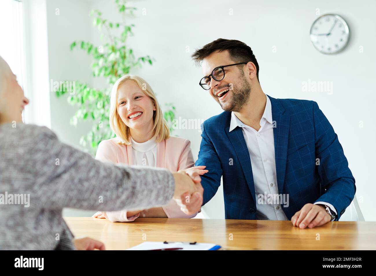 un jeune couple qui tremble les mains traite contrat d'investissement immobilier agent d'accord d'affaires poignée de main signature Banque D'Images
