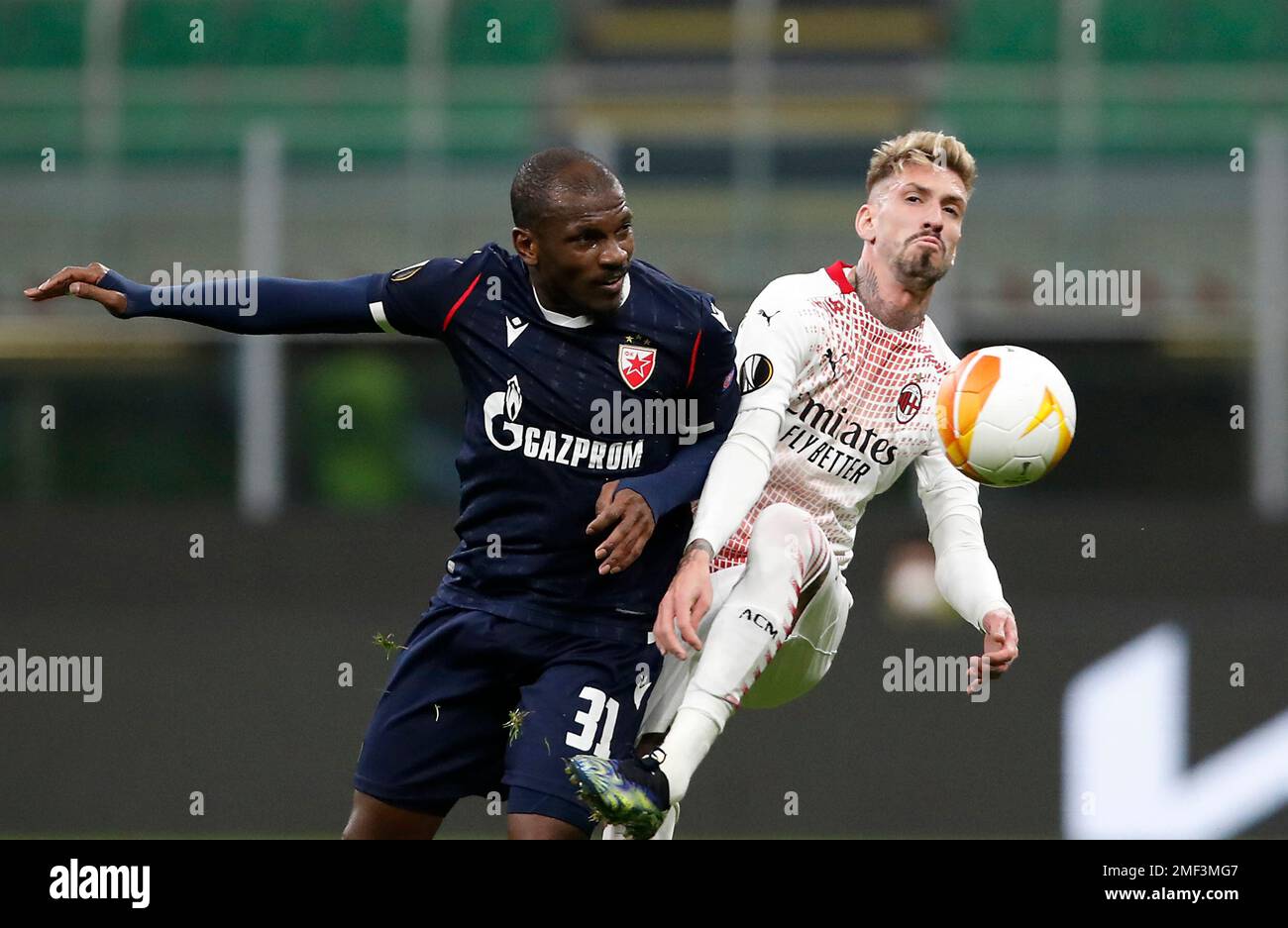 AC Milan's Samu Castillejo, right, challenges for the ball with Red Star's El Fardou Ben during the Europa League round of 32 second leg soccer match between AC Milan and Red Star Belgrade at the San Siro Stadium, in Milan, Italy, Thursday, Feb. 25, 2021. (AP Photo/Antonio Calanni) Banque D'Images