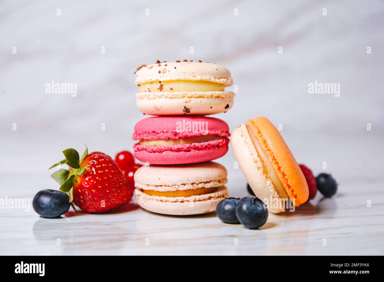 Rose macaron, orange et beige, bleu sur marbre. Un magnifique et beau dessert français. Fruits, fraises et mûres, bleuets, r Banque D'Images