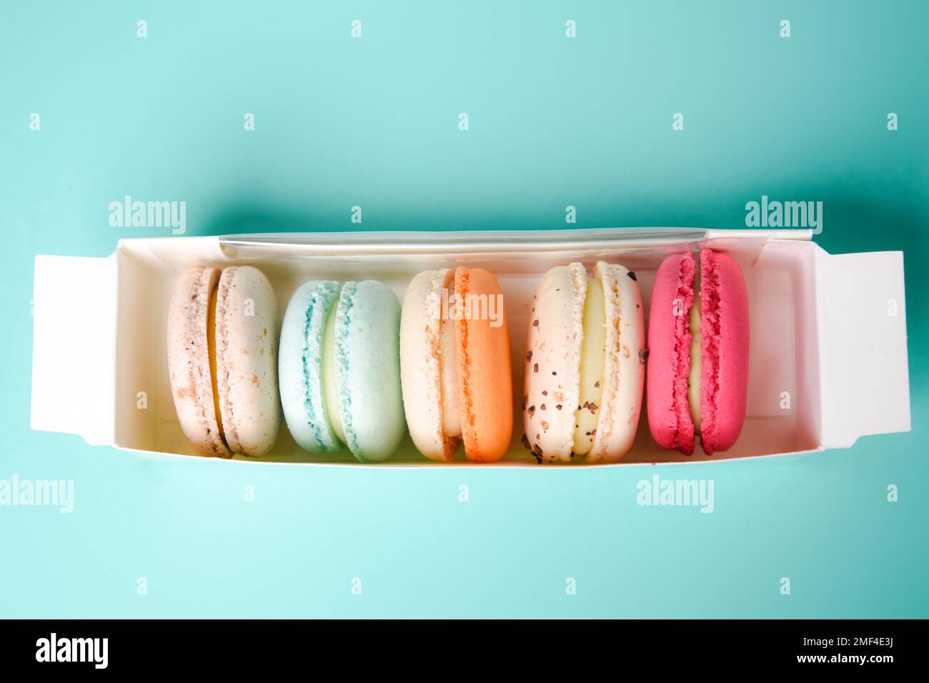 Macarons colorés. Petits gâteaux français. Macarons français doux et colorés dans une boîte sur fond bleu. Cadeau pour la Saint-Valentin Banque D'Images