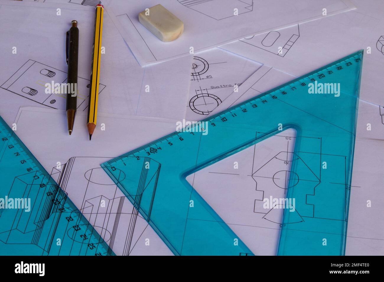 Image d'une table d'ingénieur avec des plans dessinés avec une CAO avec une règle, des carrés de jeu et des crayons de dessin en arrière-plan. Banque D'Images