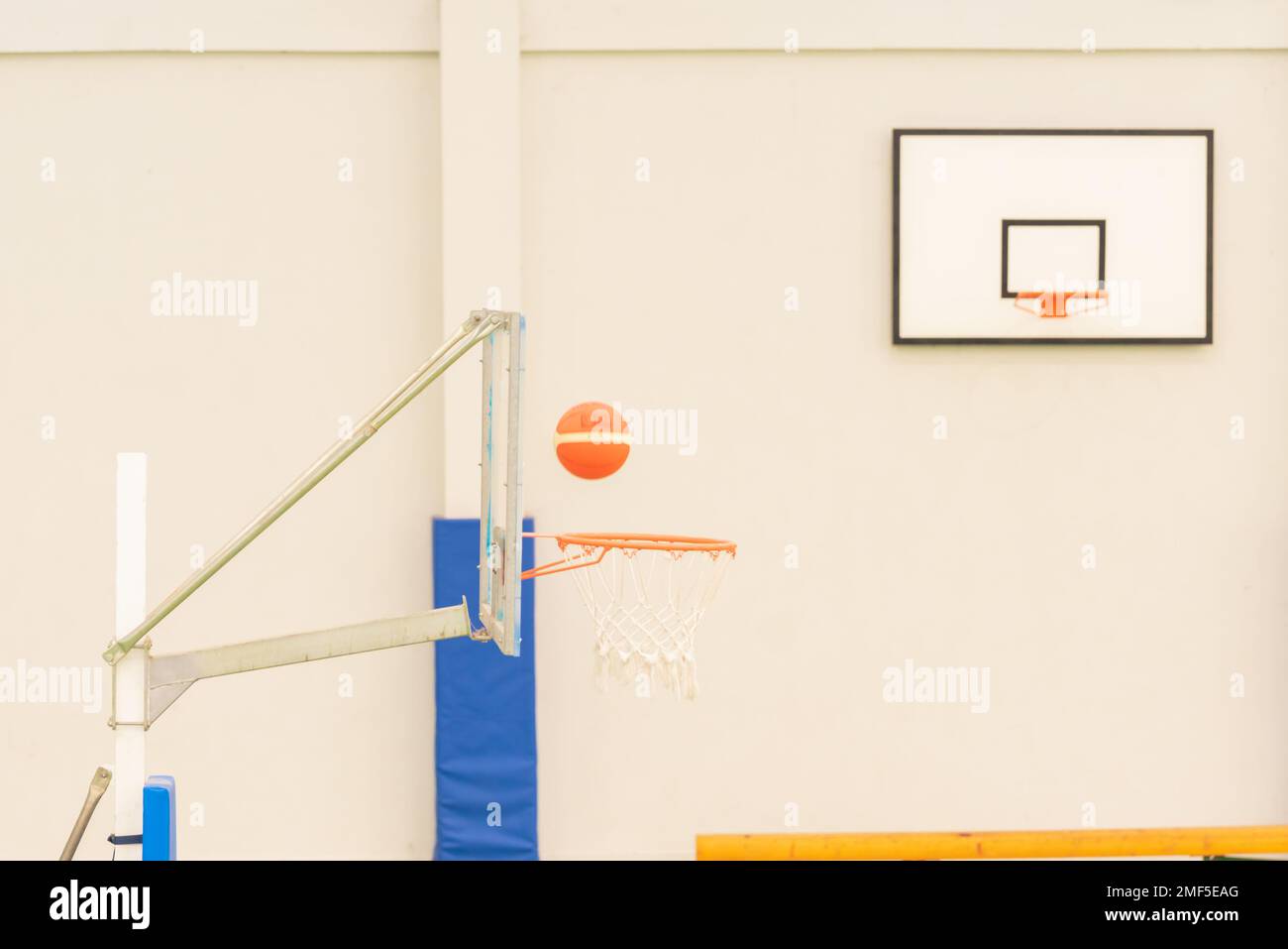 vue latérale d'un basket-ball entrant dans un mini-panier de basket-ball sur un terrain sans parquet, couleur verte Banque D'Images